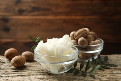 Photo of Natural shea butter, nuts and leaves on wooden table, closeup