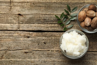 Photo of Natural shea butter, nuts and leaves on wooden table, flat lay. Space for text