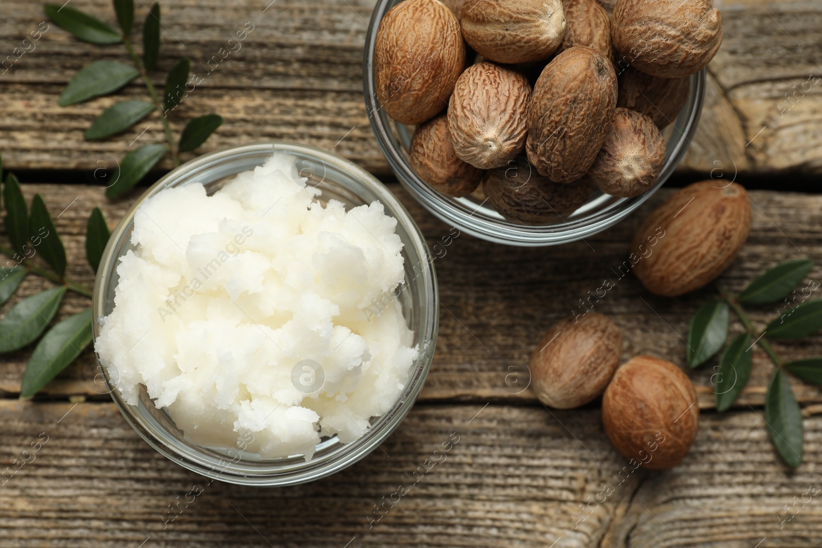 Natural shea butter, nuts and leaves on wooden table, flat lay Photo of Natural shea butter, nuts and leaves on wooden table, flat lay