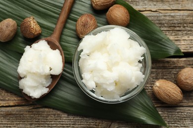 Photo of Natural shea butter and nuts on wooden table, flat lay