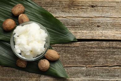 Photo of Natural shea butter and nuts on wooden table, flat lay. Space for text