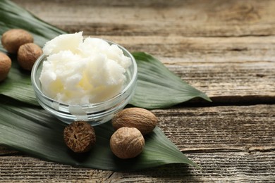 Photo of Natural shea butter and nuts on wooden table, closeup. Space for text