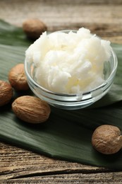 Photo of Natural shea butter and nuts on wooden table, closeup