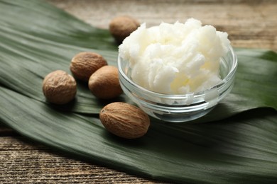 Photo of Natural shea butter and nuts on wooden table, closeup