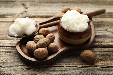 Photo of Natural shea butter and nuts on wooden table, closeup