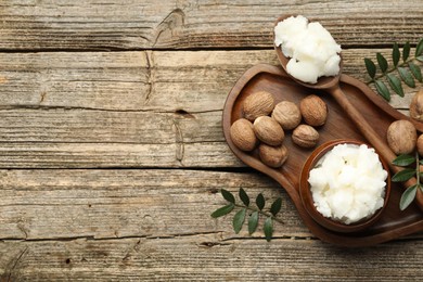 Photo of Natural shea butter, nuts and leaves on wooden table, top view. Space for text