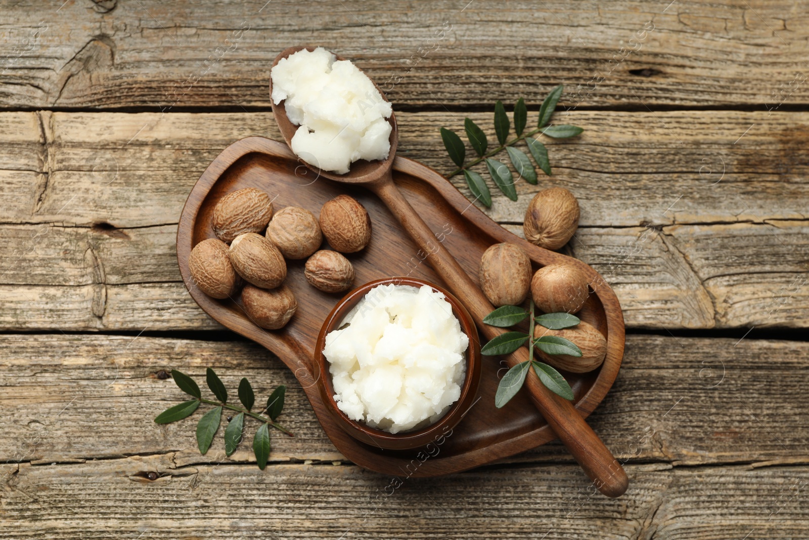 Natural shea butter, nuts and leaves on wooden table, top view Photo of Natural shea butter, nuts and leaves on wooden table, top view
