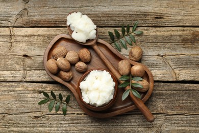 Photo of Natural shea butter, nuts and leaves on wooden table, top view