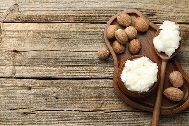 Photo of Natural shea butter and nuts on wooden table, top view. Space for text