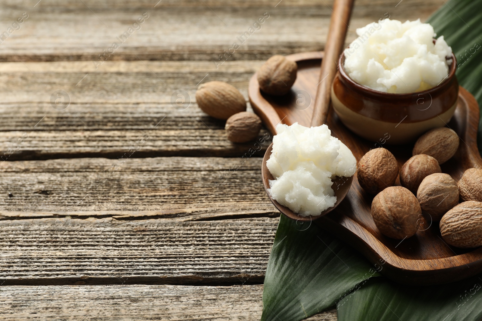 Natural shea butter, nuts and leaves on wooden table, closeup. Space for text Photo of Natural shea butter, nuts and leaves on wooden table, closeup. Space for text