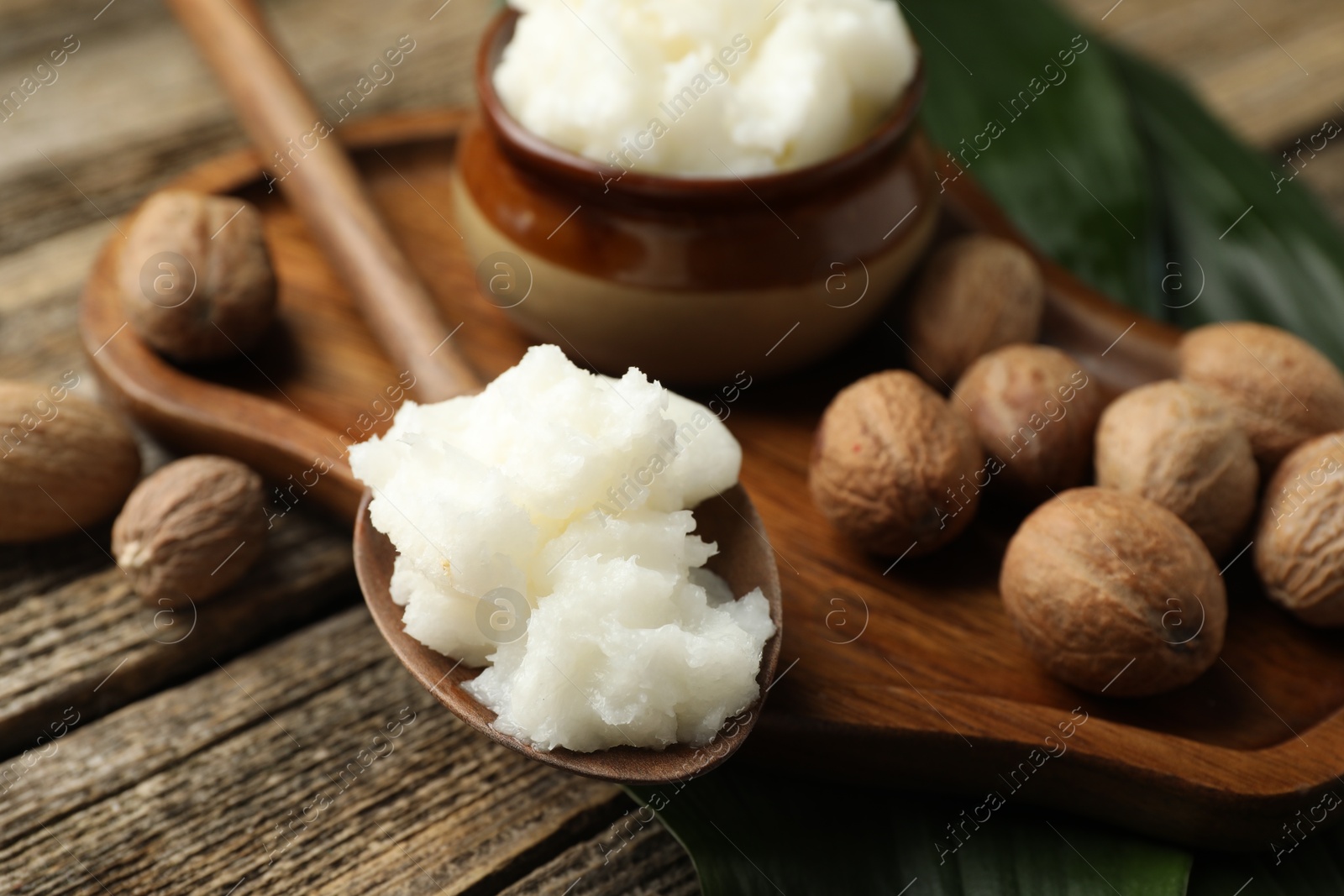 Natural shea butter, nuts and leaves on wooden table, closeup Photo of Natural shea butter, nuts and leaves on wooden table, closeup