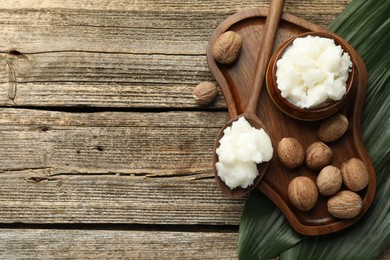 Photo of Natural shea butter, nuts and leaves on wooden table, top view. Space for text