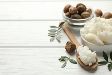 Photo of Natural shea butter, nuts and leaves on white wooden table, closeup. Space for text
