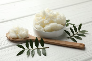 Photo of Natural shea butter and leaves on white wooden table, closeup