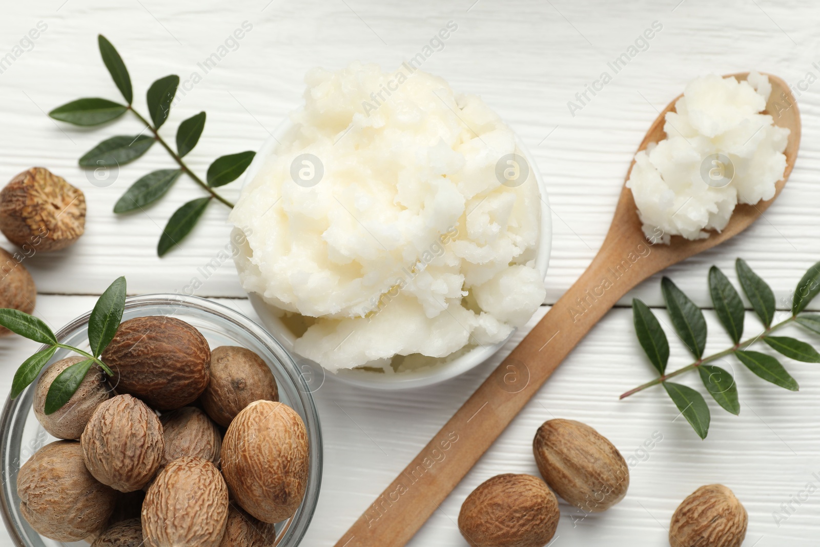Natural shea butter, nuts and leaves on white wooden table, flat lay Photo of Natural shea butter, nuts and leaves on white wooden table, flat lay