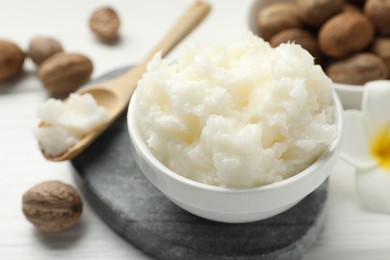 Photo of Natural shea butter and nuts on white wooden table, closeup