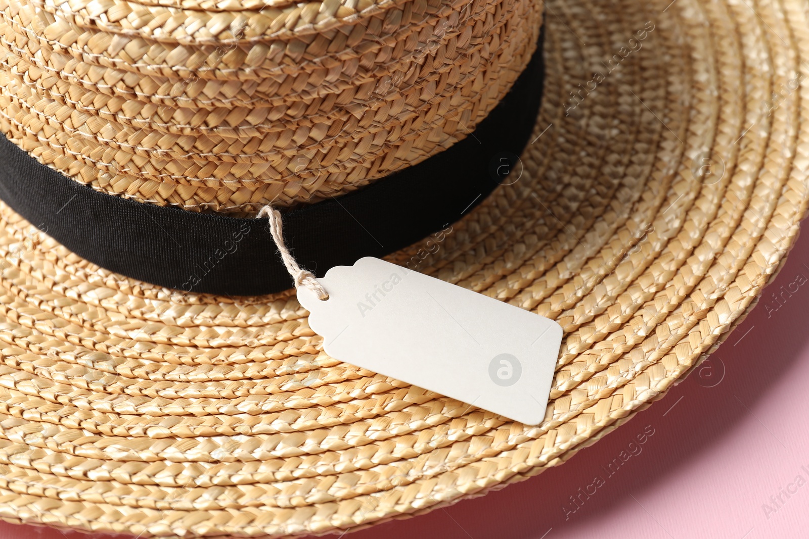 Straw hat with tag on pink background, closeup Photo of Straw hat with tag on pink background, closeup