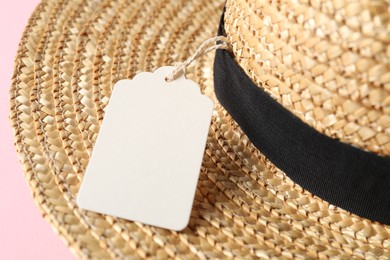 Photo of Straw hat with tag on pink background, closeup