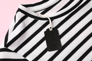 Photo of Striped t-shirt with tag on pink background, top view