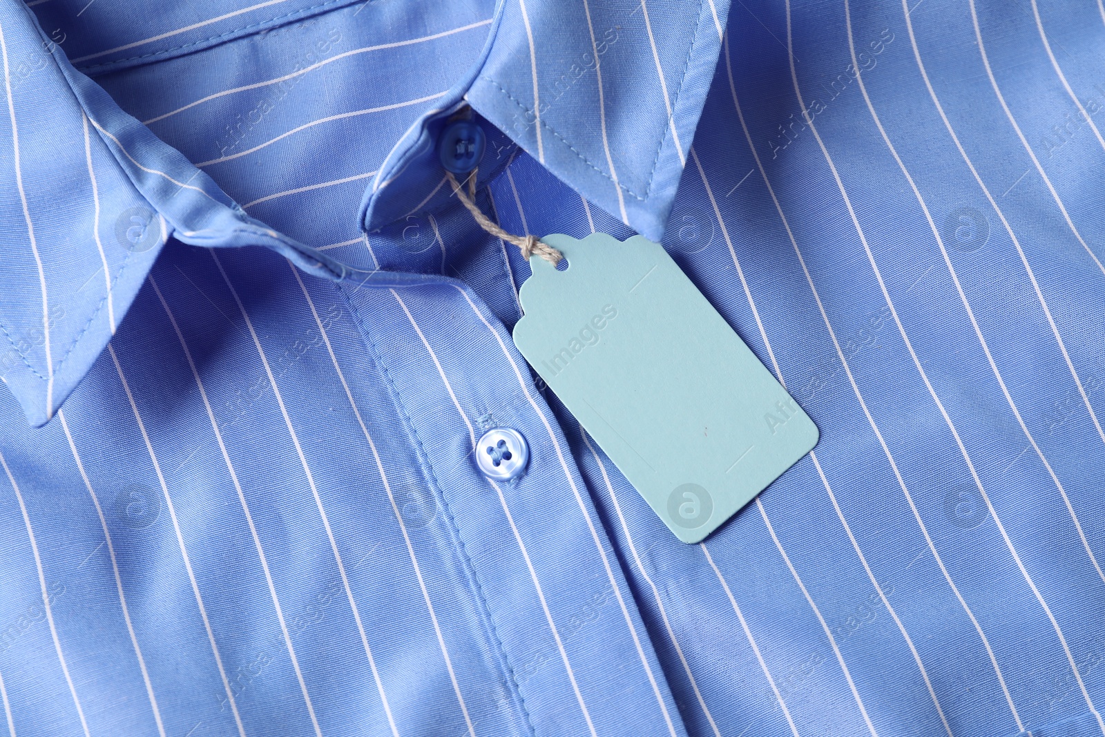 Cardboard tag on light blue shirt, top view Photo of Cardboard tag on light blue shirt, top view
