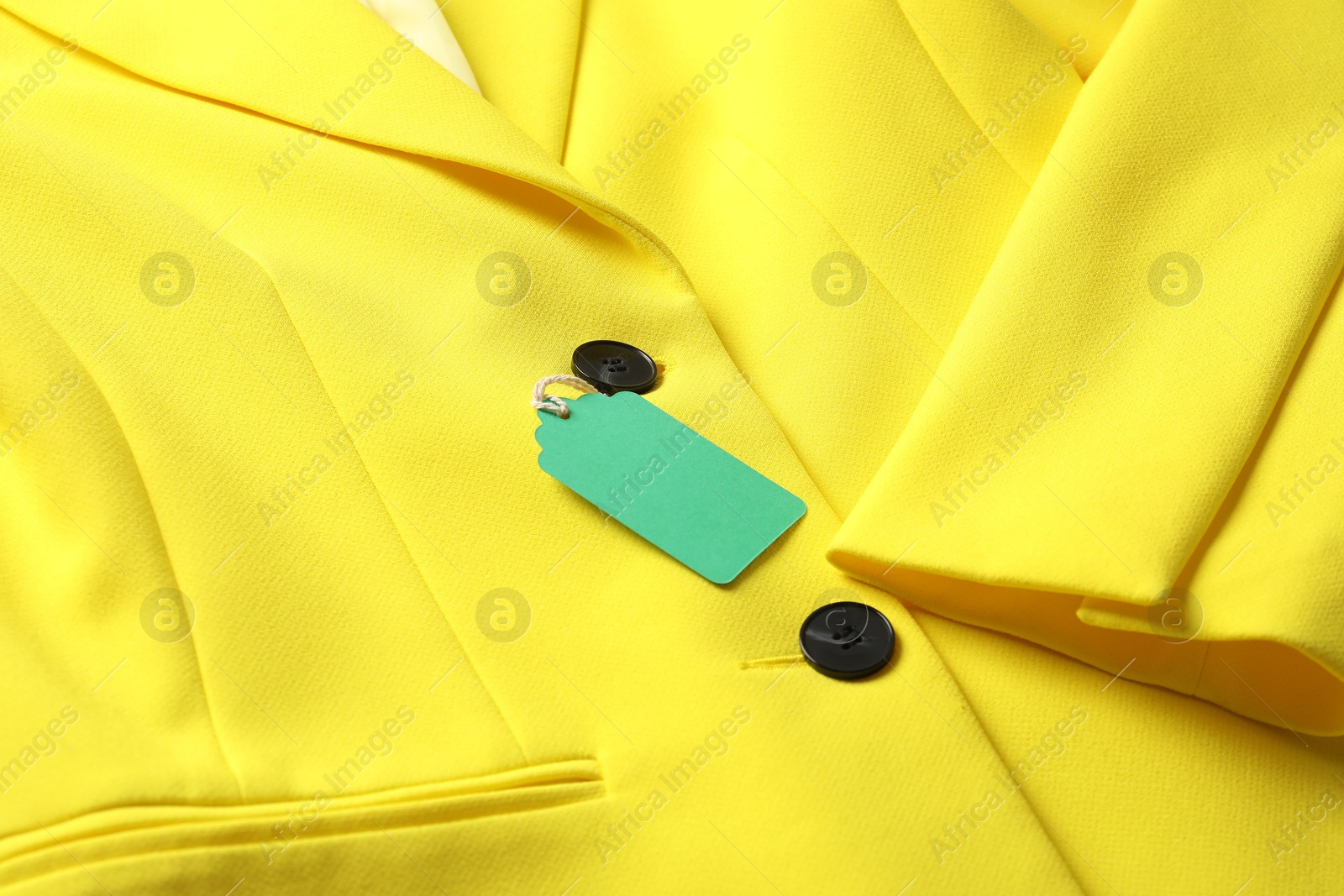 Cardboard tag on yellow jacket, closeup view Photo of Cardboard tag on yellow jacket, closeup view