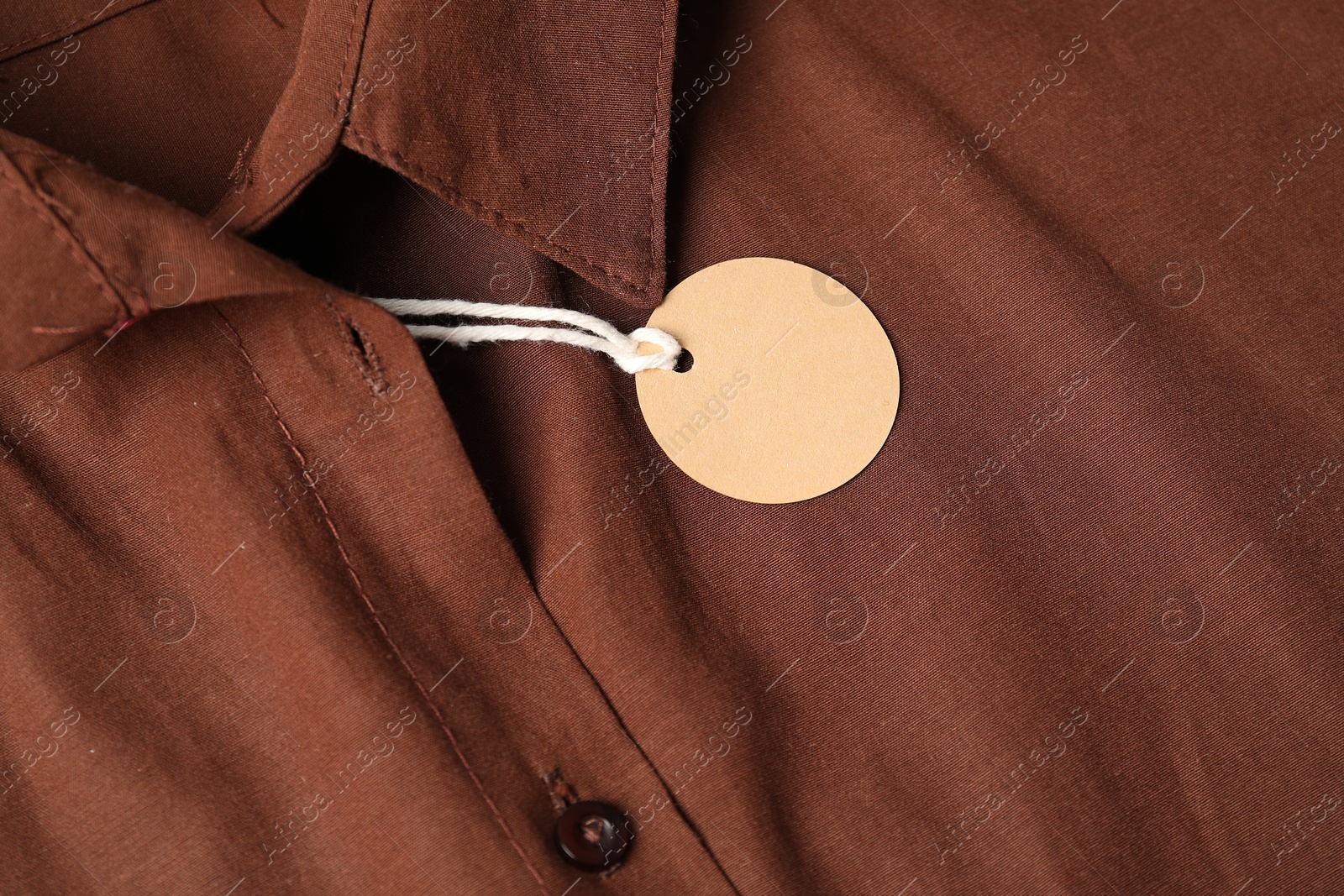 Cardboard tag on brown shirt, above view Photo of Cardboard tag on brown shirt, above view