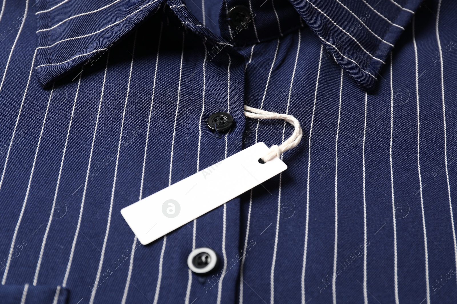 Cardboard tag on striped shirt, closeup view Photo of Cardboard tag on striped shirt, closeup view