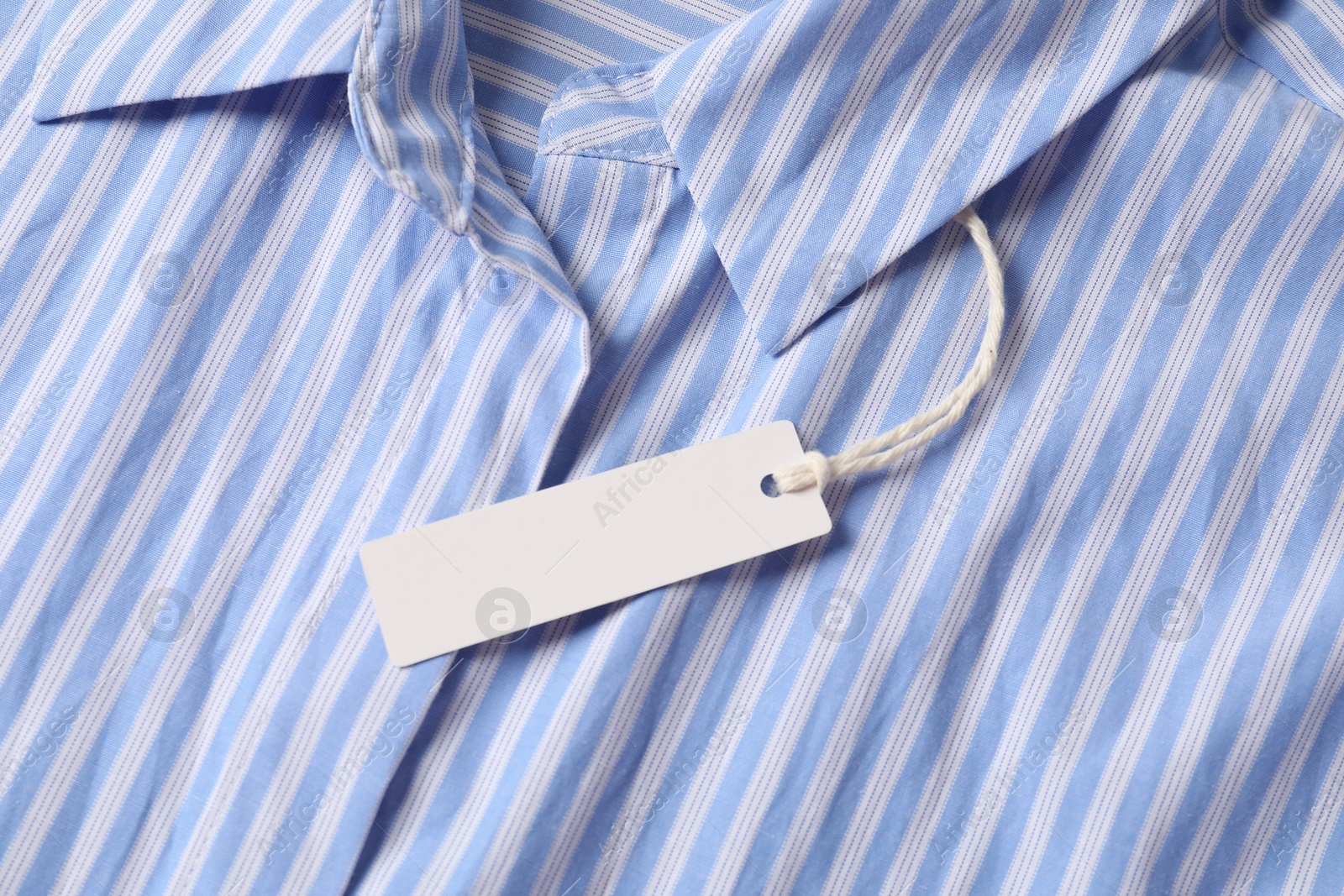 Cardboard tag on striped shirt, top view Photo of Cardboard tag on striped shirt, top view