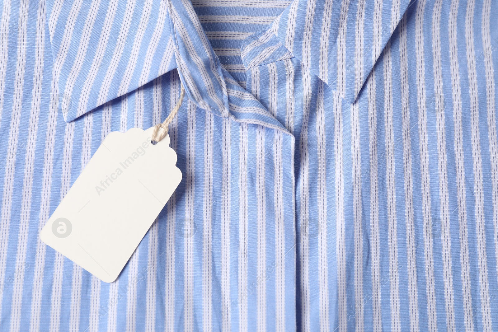Cardboard tag on striped shirt, top view Photo of Cardboard tag on striped shirt, top view