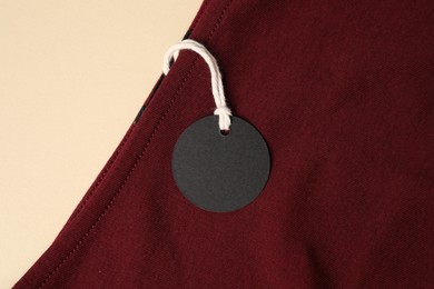 Photo of Red garment with tag on beige background, top view