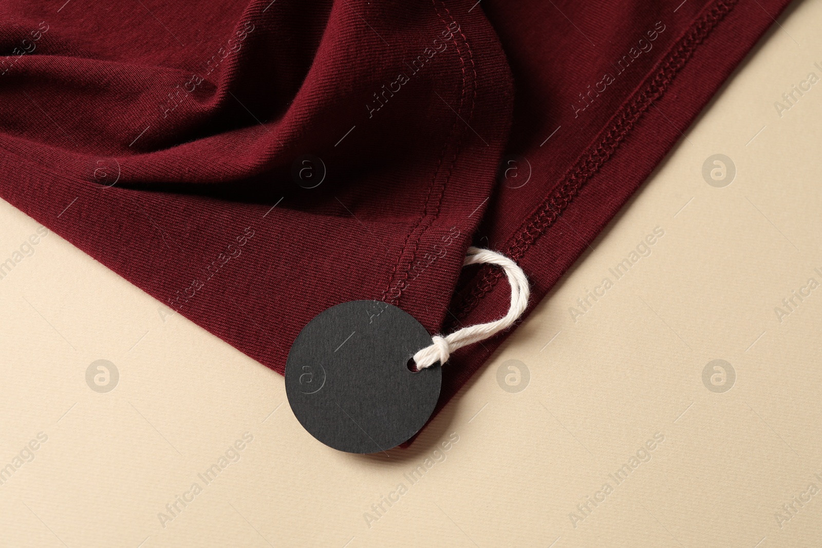 Red garment with tag on beige background, top view Photo of Red garment with tag on beige background, top view