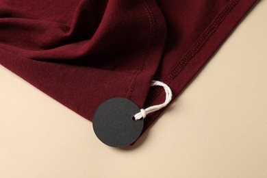 Photo of Red garment with tag on beige background, top view