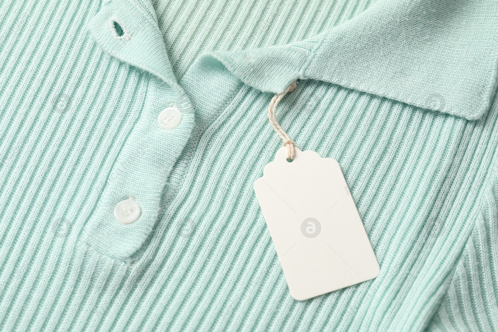 Cardboard tag on turquoise garment, above view Photo of Cardboard tag on turquoise garment, above view