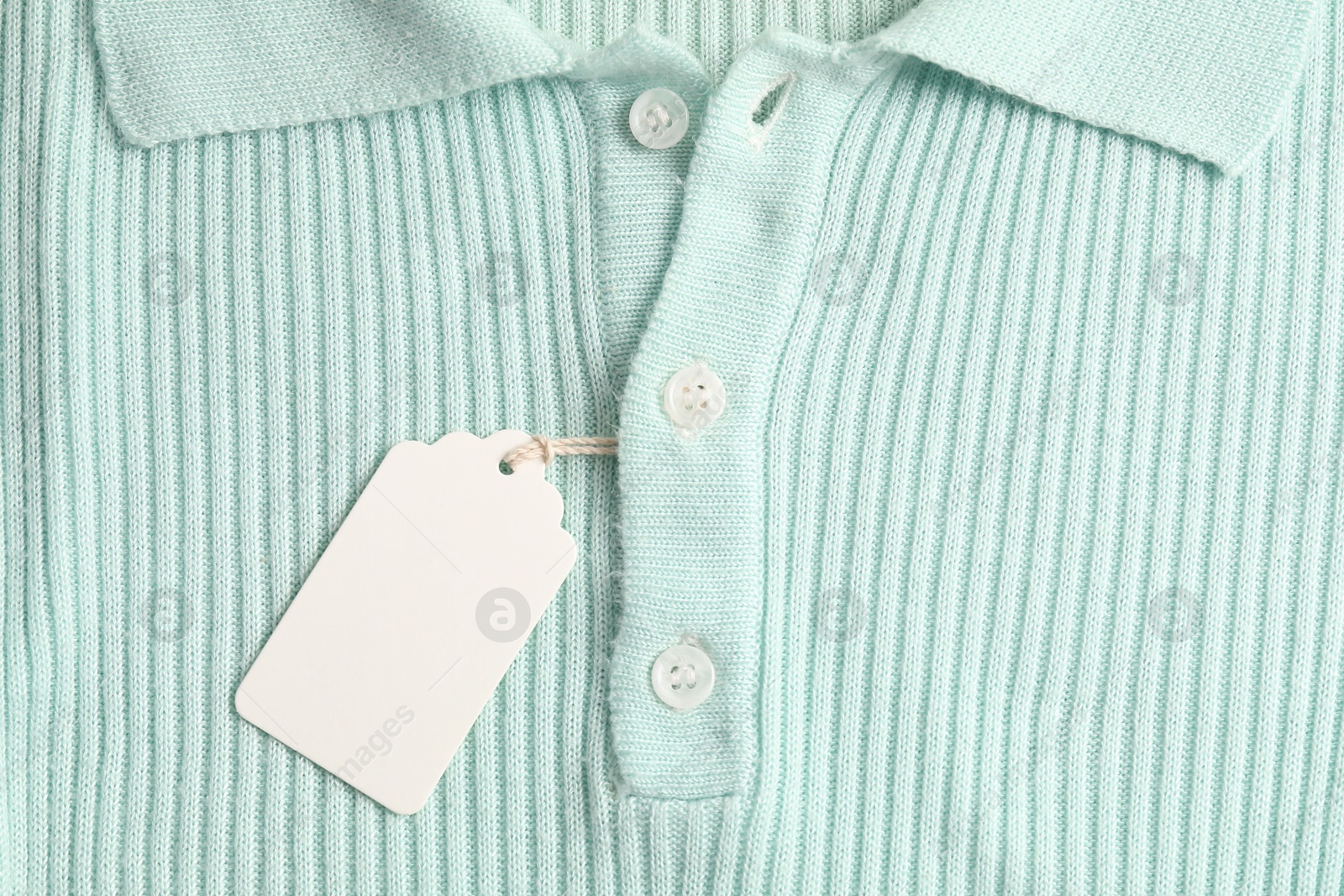 Cardboard tag on turquoise garment, top view Photo of Cardboard tag on turquoise garment, top view