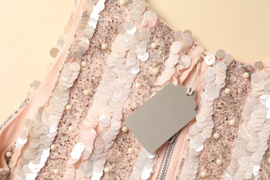 Photo of Stylish dress with tag on beige background, top view