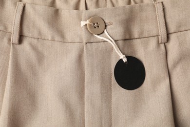 Photo of Cardboard tag on beige pants, top view