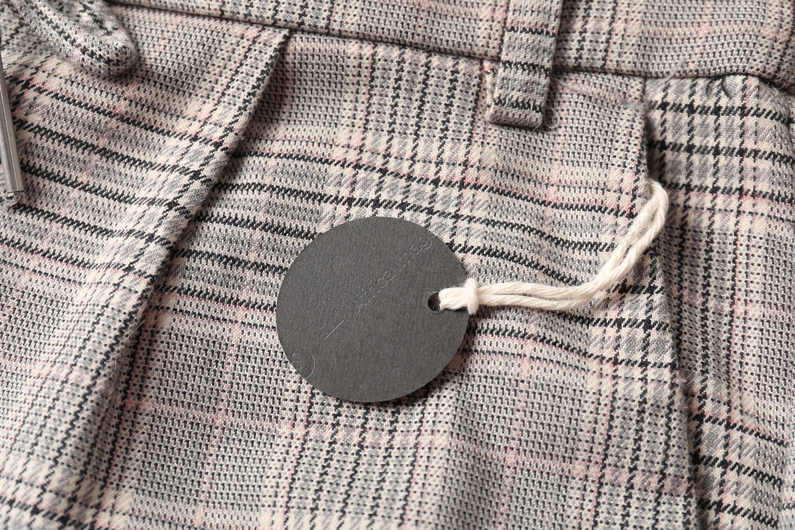 Cardboard tag on checkered pants, top view Photo of Cardboard tag on checkered pants, top view