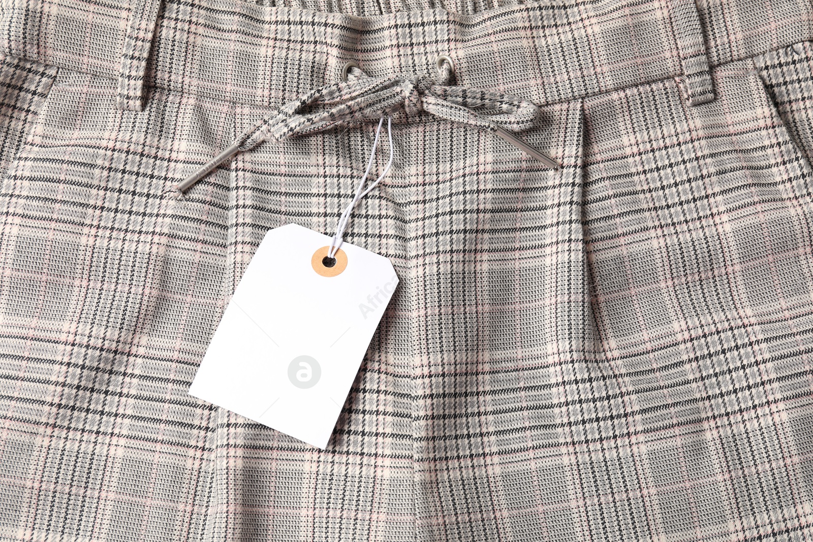 Cardboard tag on checkered pants, above view Photo of Cardboard tag on checkered pants, above view