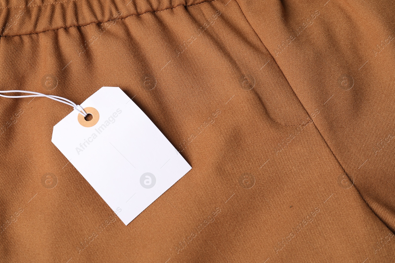 Cardboard tag on brown pants, above view Photo of Cardboard tag on brown pants, above view