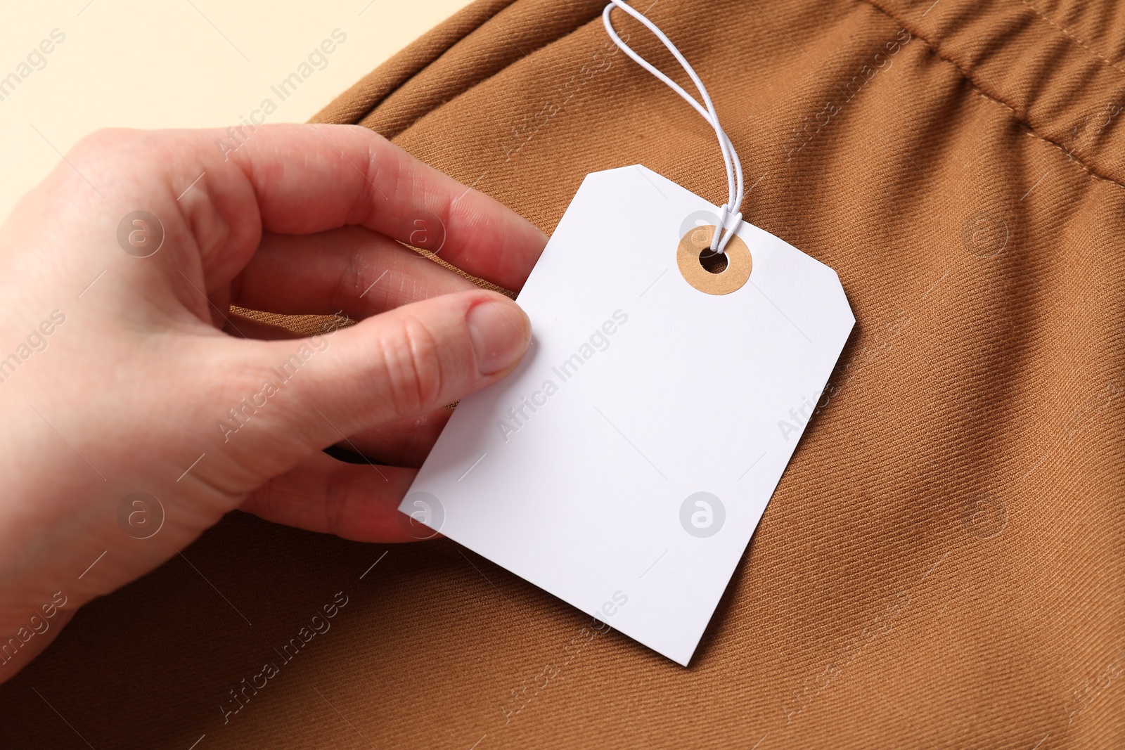 Woman holding tag of brown garment, above view Photo of Woman holding tag of brown garment, above view