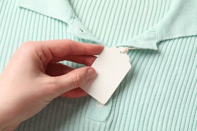 Photo of Woman holding tag of turquoise garment, above view