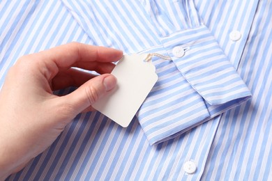 Photo of Woman holding tag of striped shirt, above view