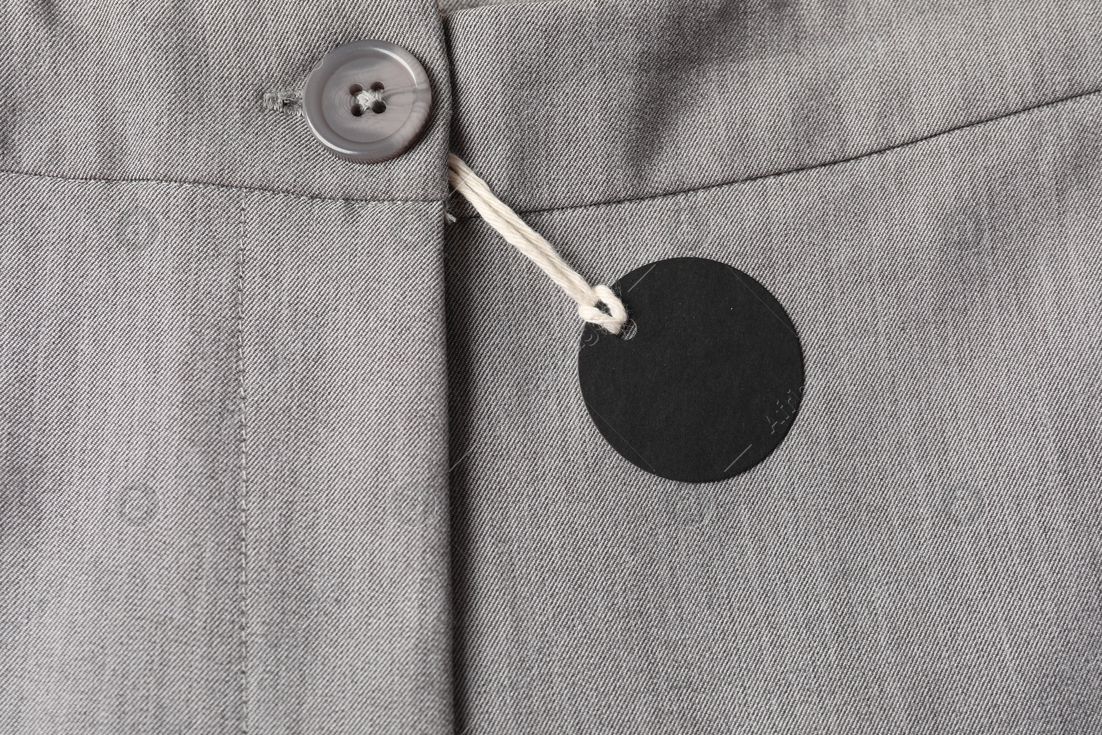 Cardboard tag on grey pants, top view Photo of Cardboard tag on grey pants, top view