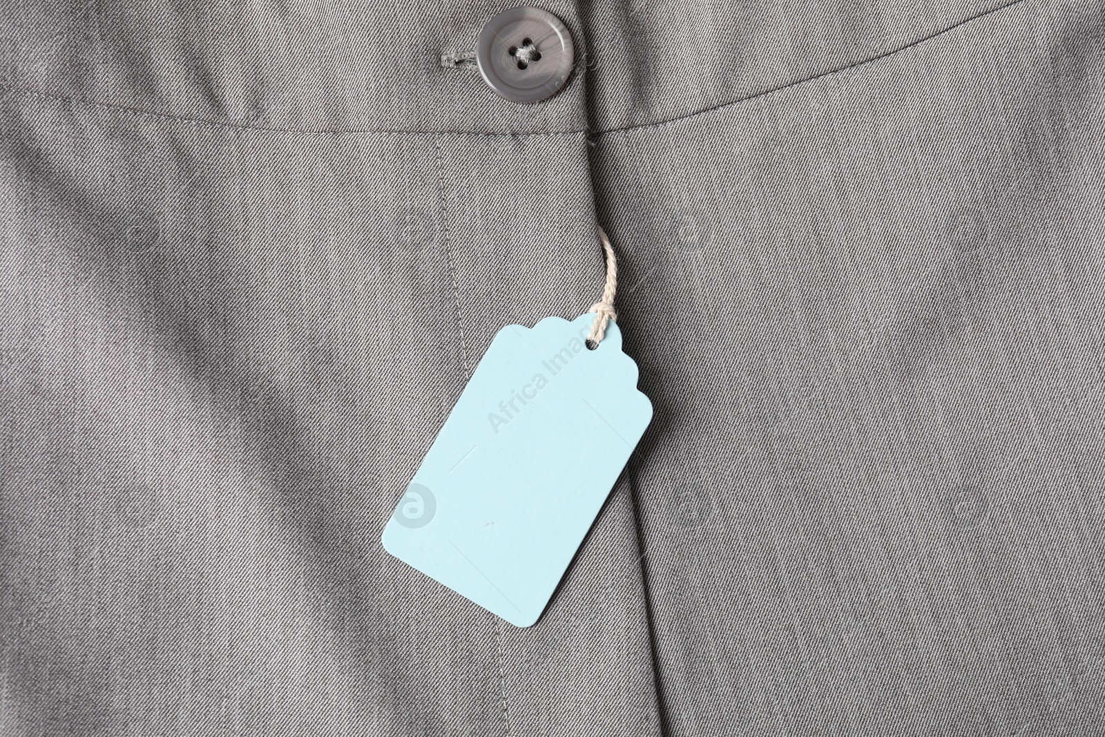 Cardboard tag on grey pants, top view Photo of Cardboard tag on grey pants, top view