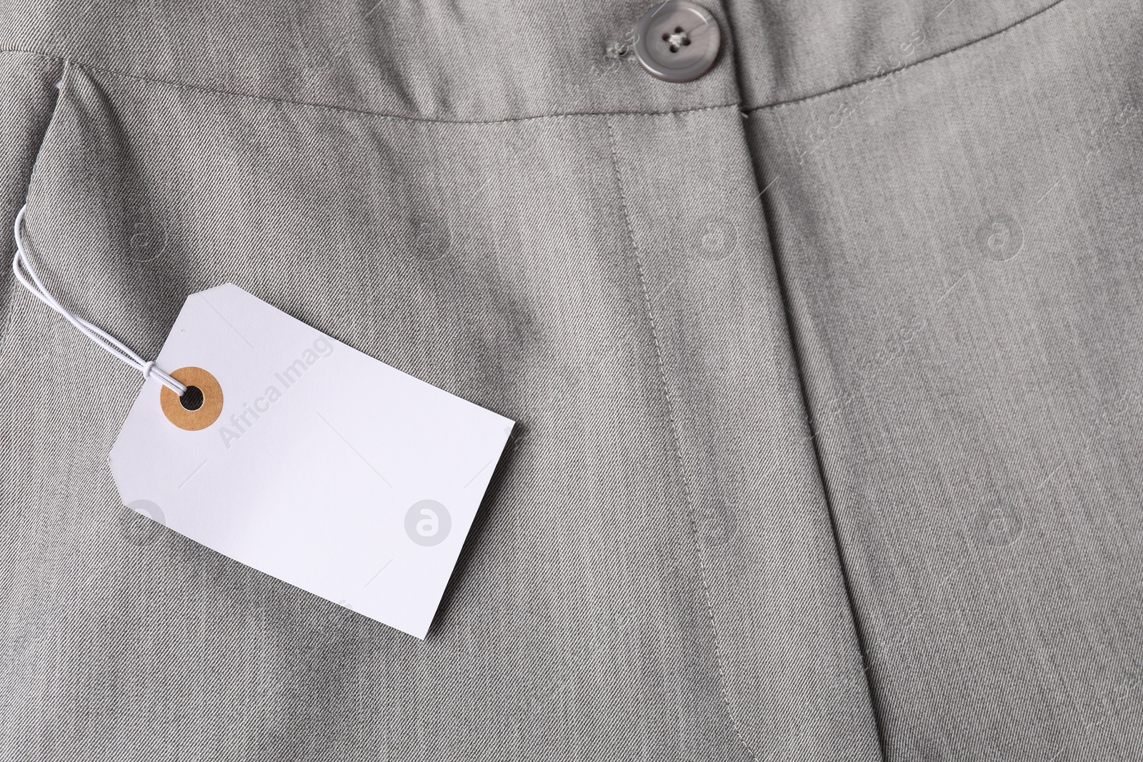 Cardboard tag on grey pants, top view Photo of Cardboard tag on grey pants, top view