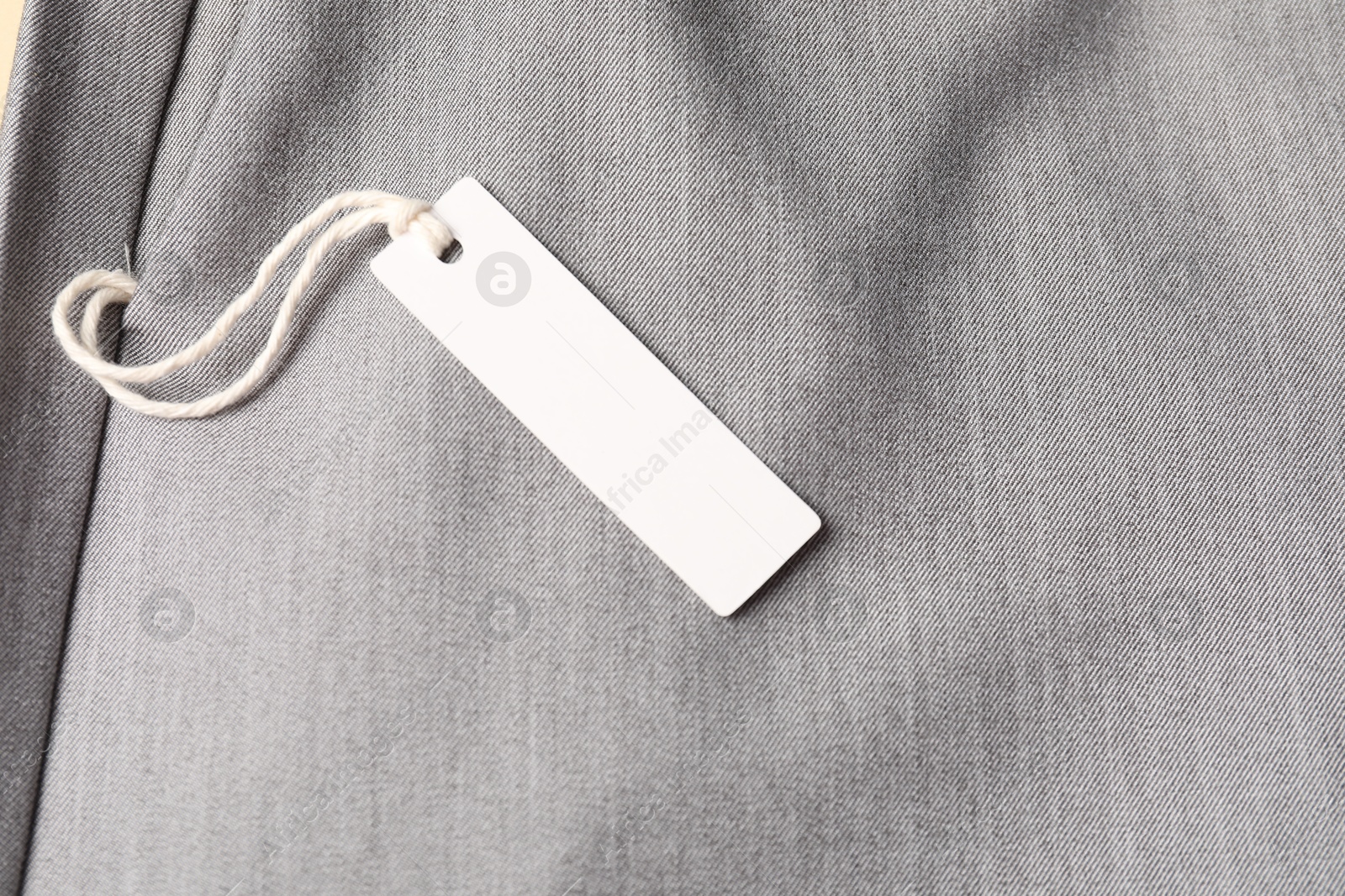 Cardboard tag on grey pants, above view Photo of Cardboard tag on grey pants, above view