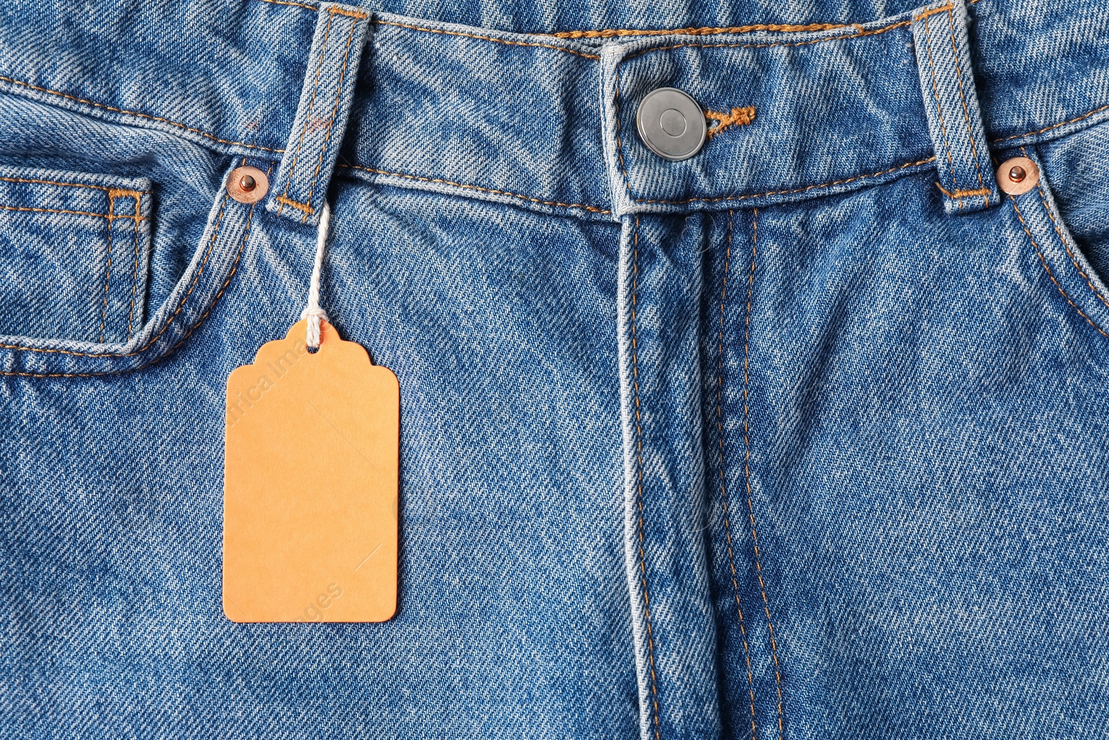 Cardboard tag on blue jeans, top view Photo of Cardboard tag on blue jeans, top view