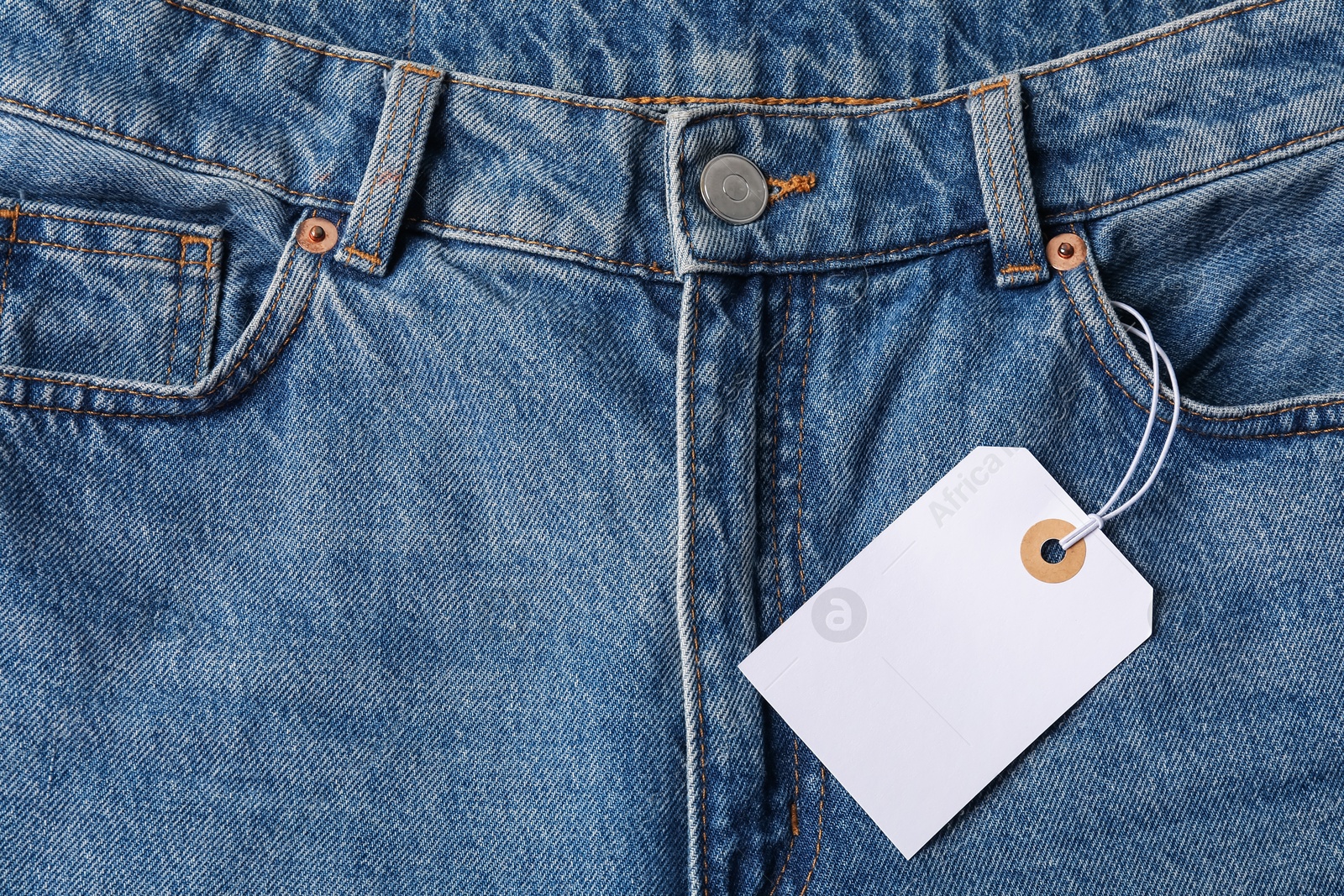 Cardboard tag on blue jeans, top view Photo of Cardboard tag on blue jeans, top view