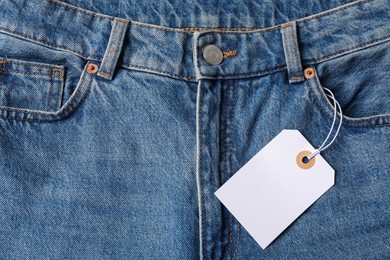 Photo of Cardboard tag on blue jeans, top view