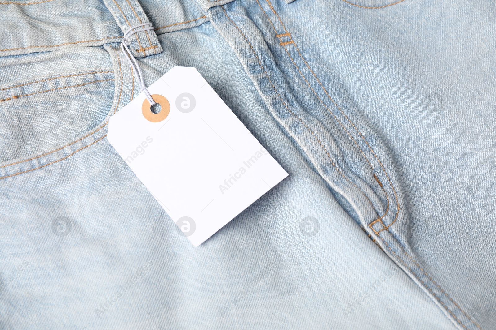 Cardboard tag on light blue jeans, above view Photo of Cardboard tag on light blue jeans, above view